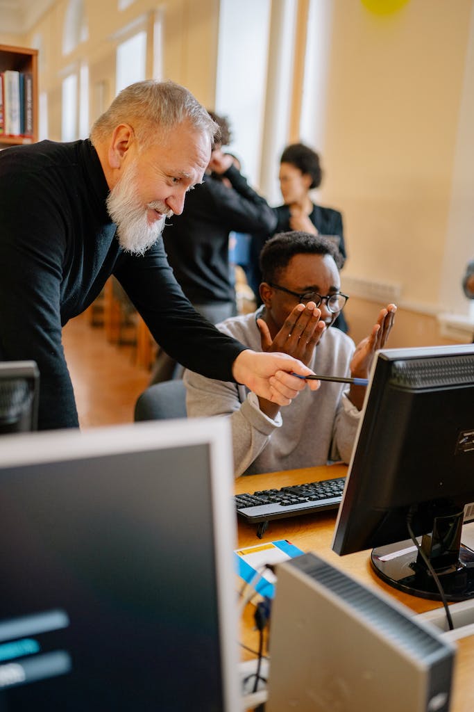 Profesor asistiendo al alumno. Señalando en la pantalla de la computadora